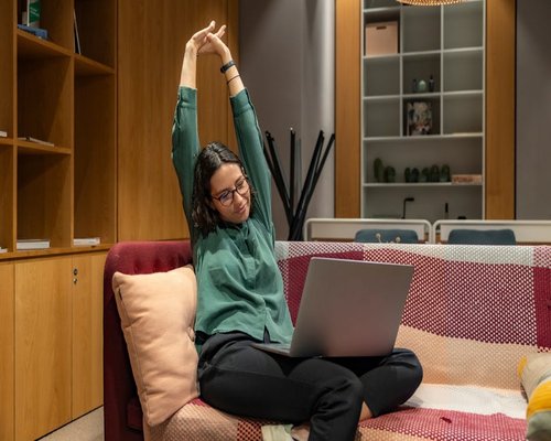 Person standing up from an office chair stretching arms slightly