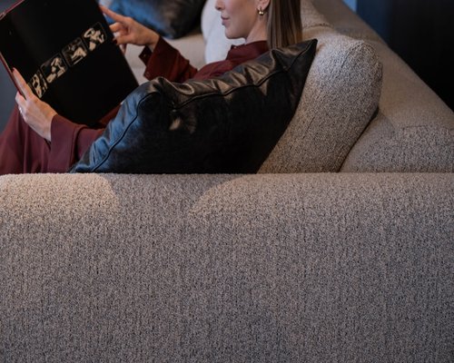 Person shifting position comfortably on a sofa while reading